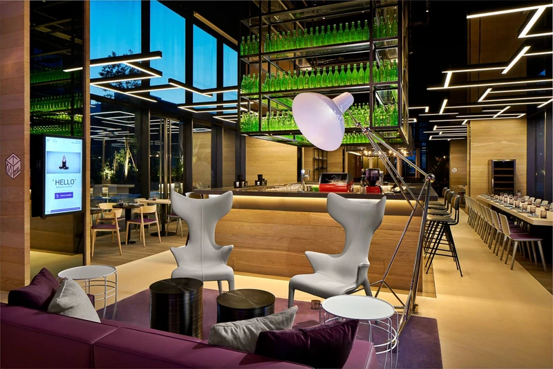 Evening lobby lounge with wing chairs, purple sofas and bottle installation