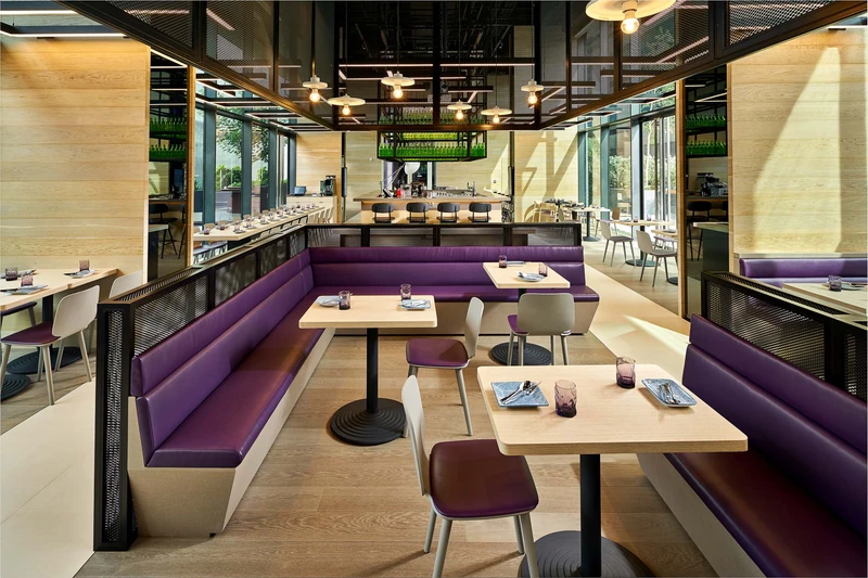Restaurant with purple banquette seating, oak tables and open kitchen