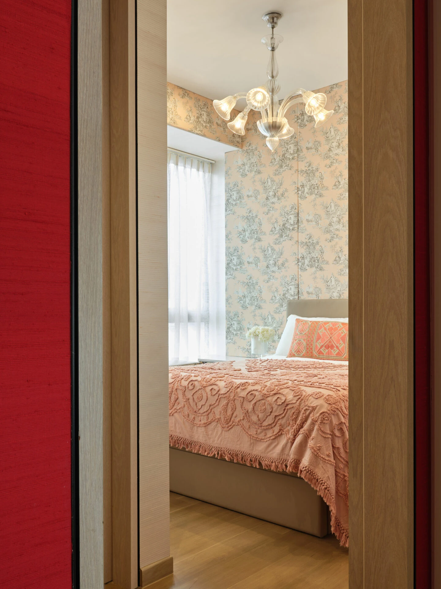 Bedroom entrance with red accent door, floral wallpaper and warm lighting