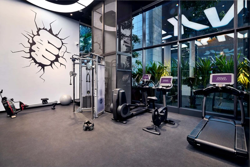 Fitness centre with cardio equipment and fist mural through glass walls