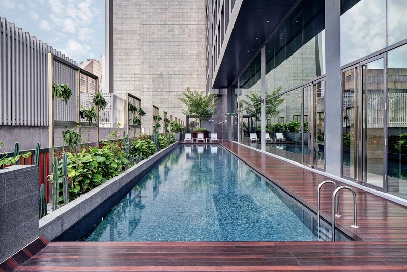 Rooftop lap pool with white loungers and tropical plantings