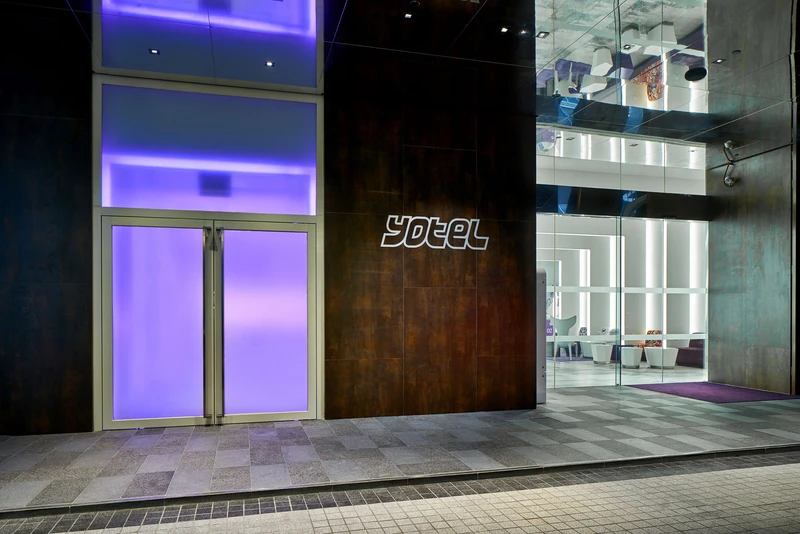 Corten steel entrance with purple glass door and illuminated lobby