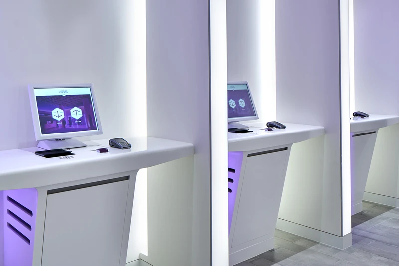 Self-service check-in kiosks with lavender ambient lighting