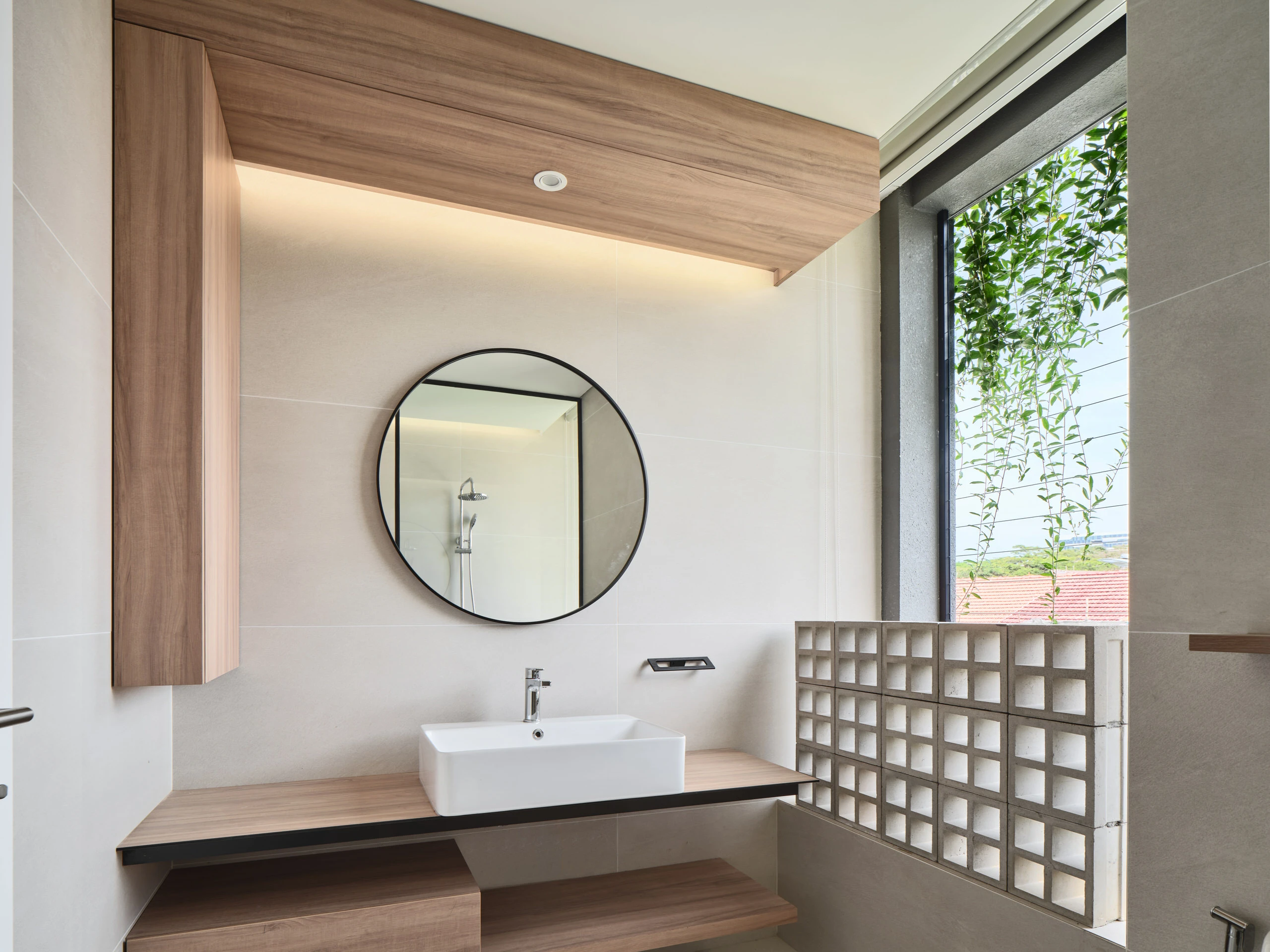 Modern bathroom with round mirror and wood accents in residential home.