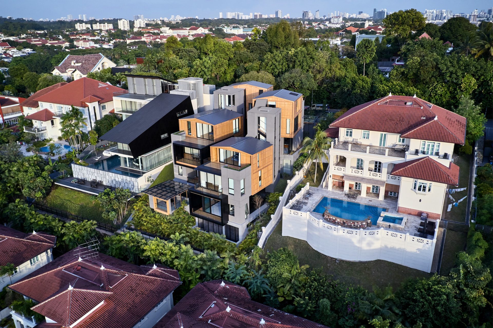 High aerial of modern house among colonial bungalows at golden hour