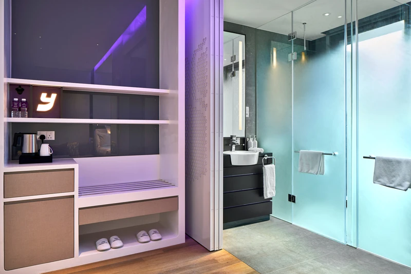 Bathroom with rain shower and purple accent lighting beside minibar