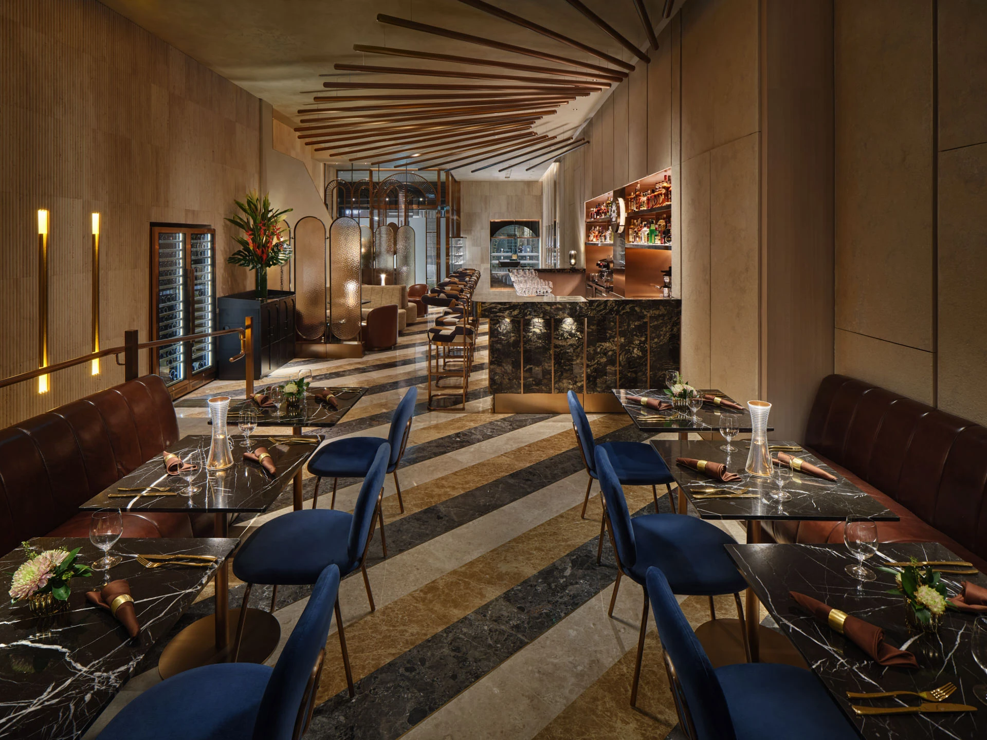 Dining hall with navy velvet chairs, leather banquettes and wine display