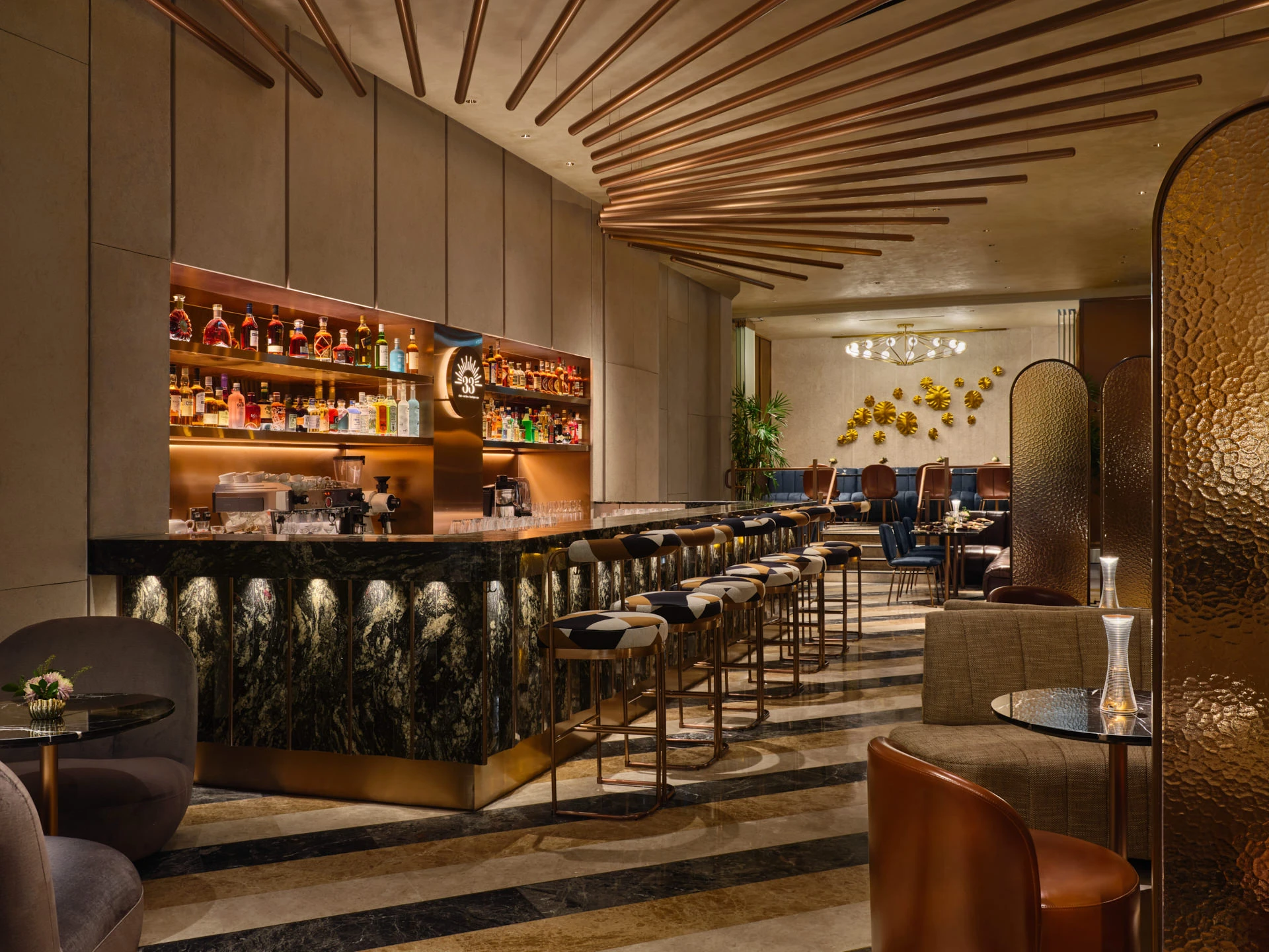 Bar with green marble counter, copper ceiling rods and brass-trimmed stools