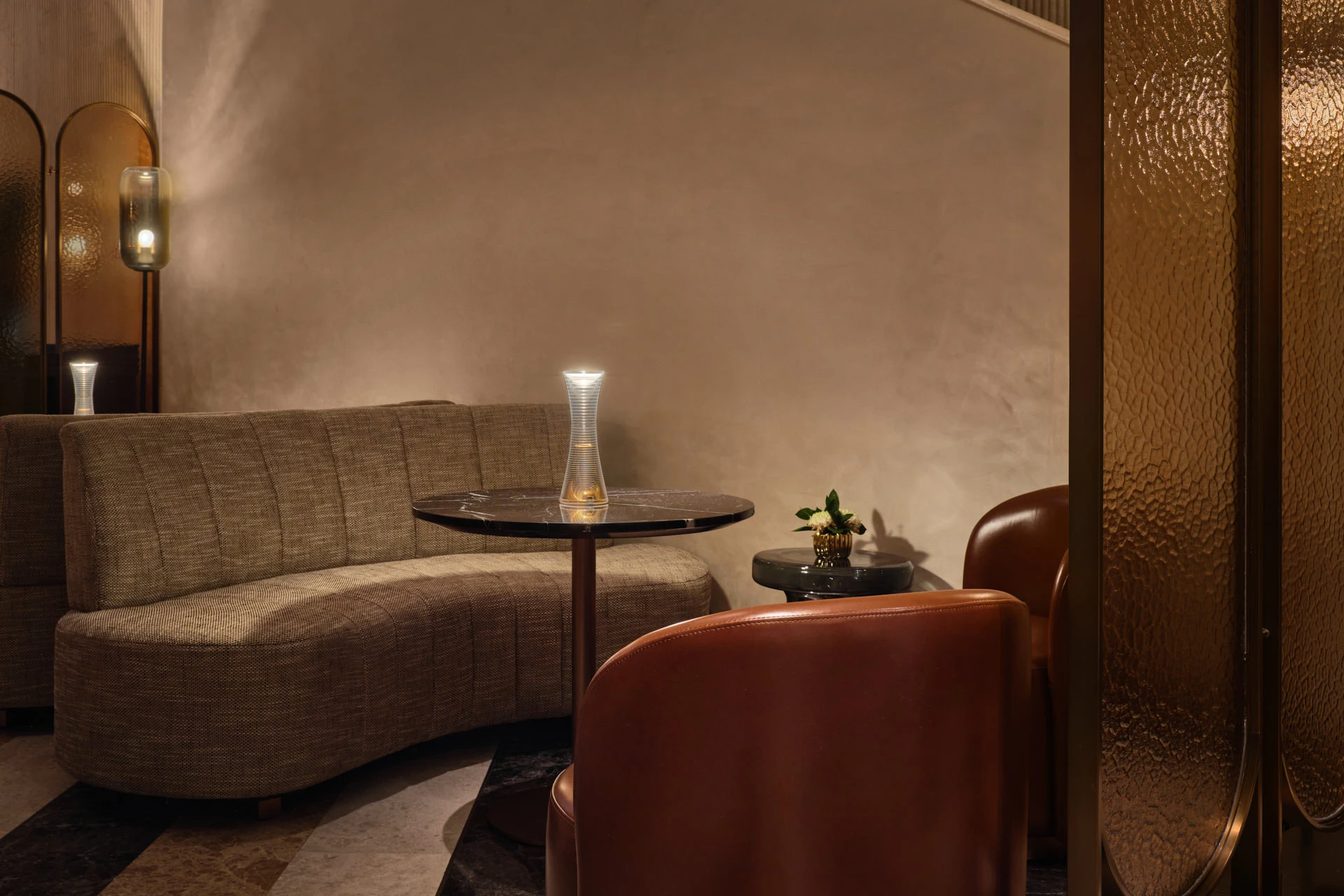 Intimate lounge with tufted sofa, barrel chair and brass wall sconce