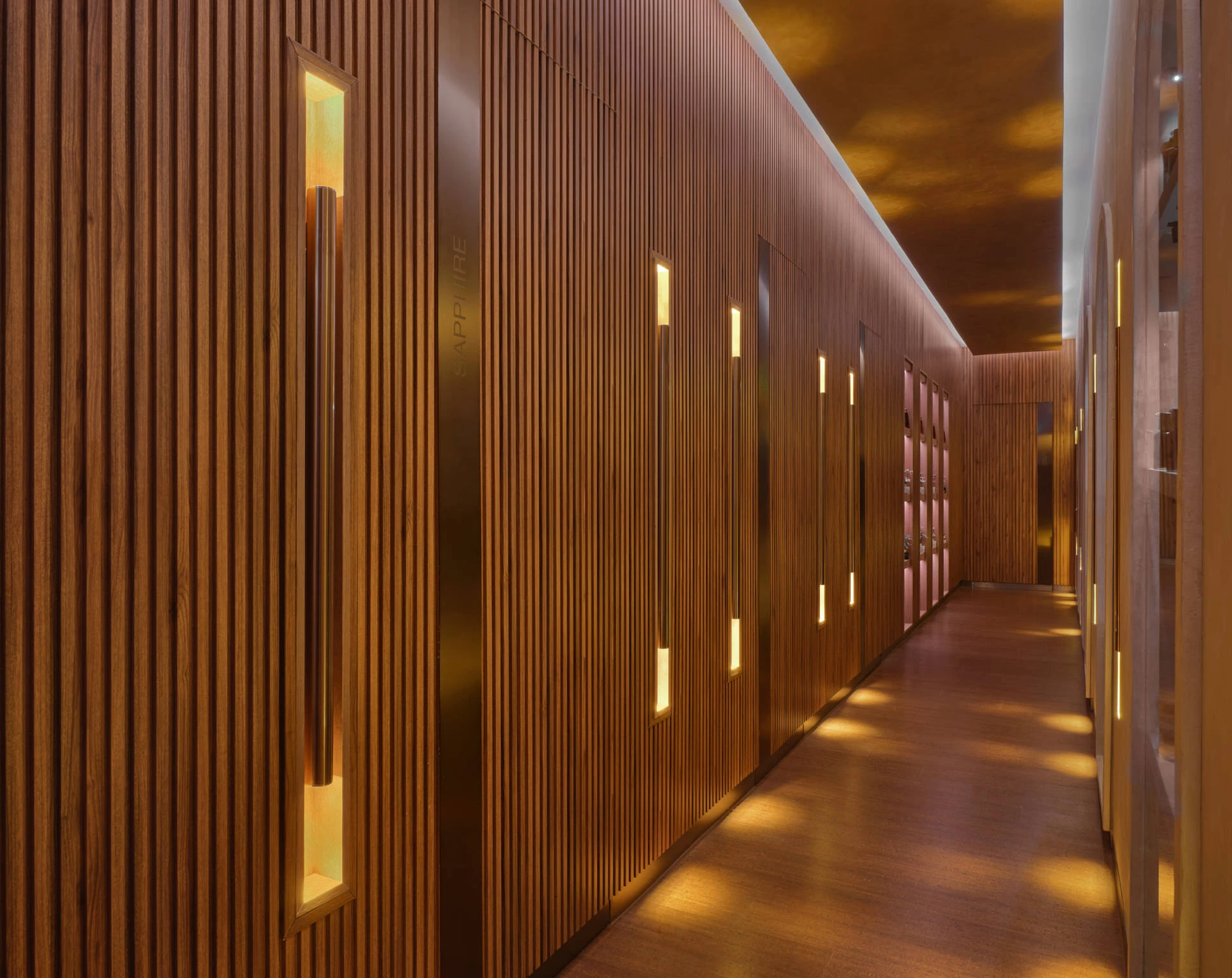 Teak spa corridor with amber-lit recessed niches and arched mirror