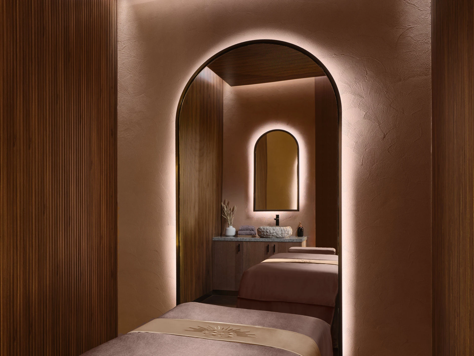 Backlit archway framing spa treatment room with nested arched mirror