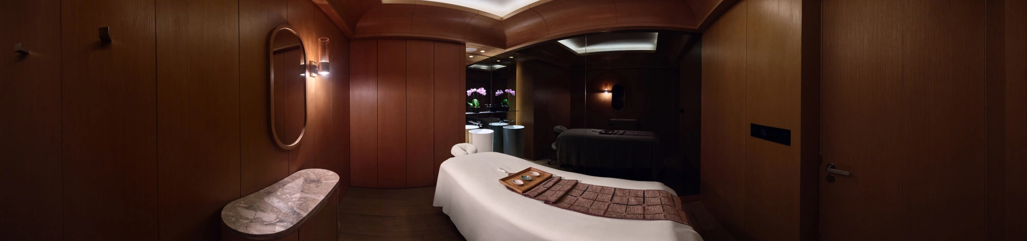 360 panorama of Conrad Centennial Singapore spa treatment room with timber-paneled walls and massage bed