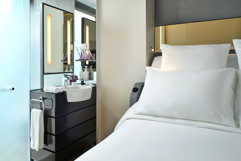Cabin bathroom with black vanity, basin and backlit mirror beside bed