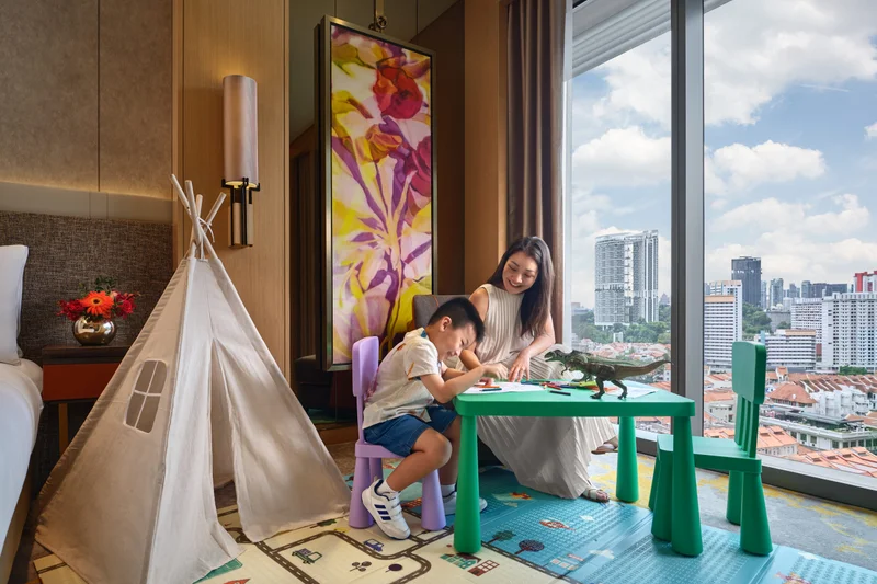 Sofitel Singapore City Centre family room lifestyle scene with parent and child beside a play tent and city skyline views