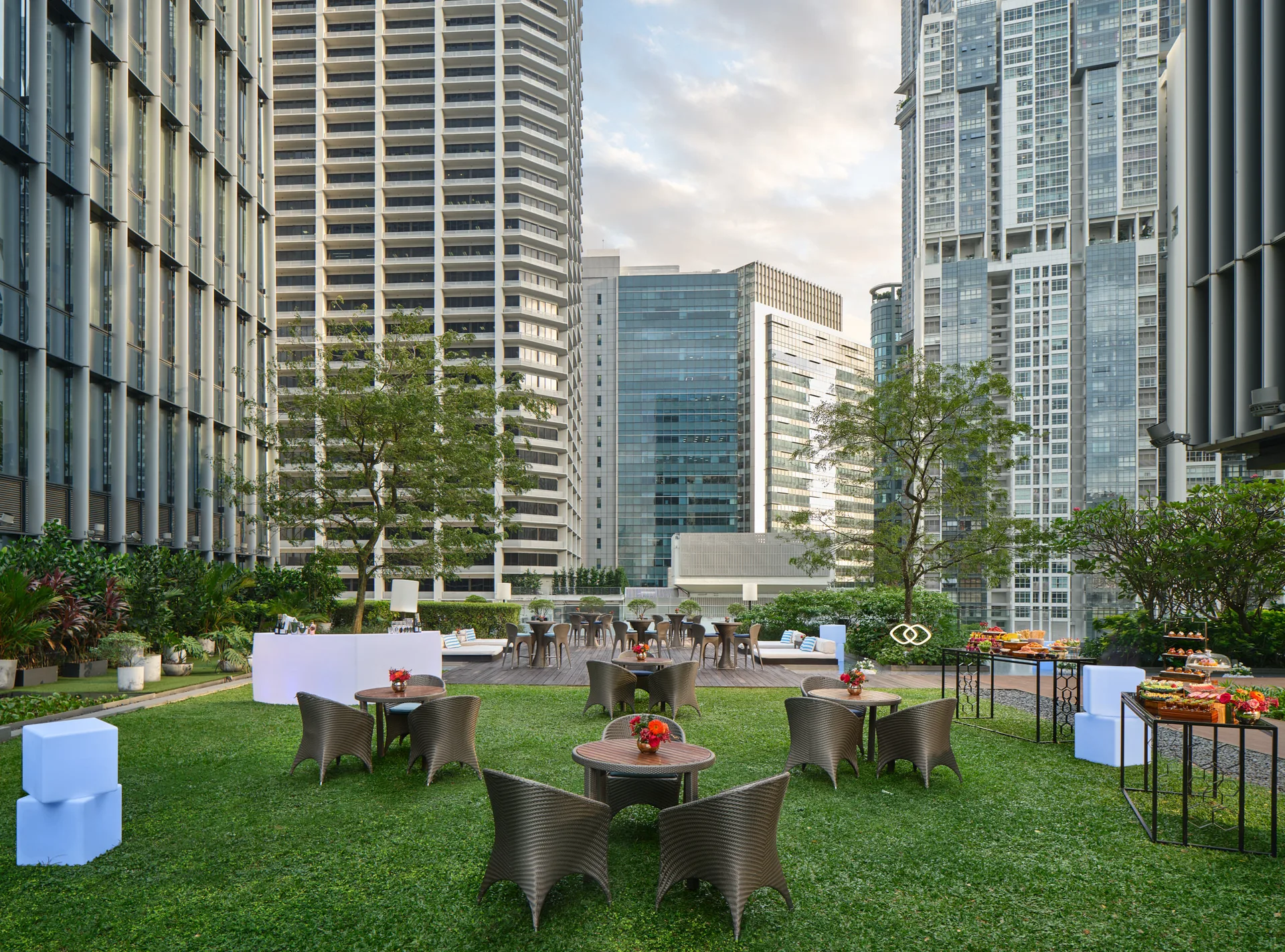 Outdoor lawn event setup at Sofitel Singapore City Centre with city towers, garden seating and hospitality lounge tables