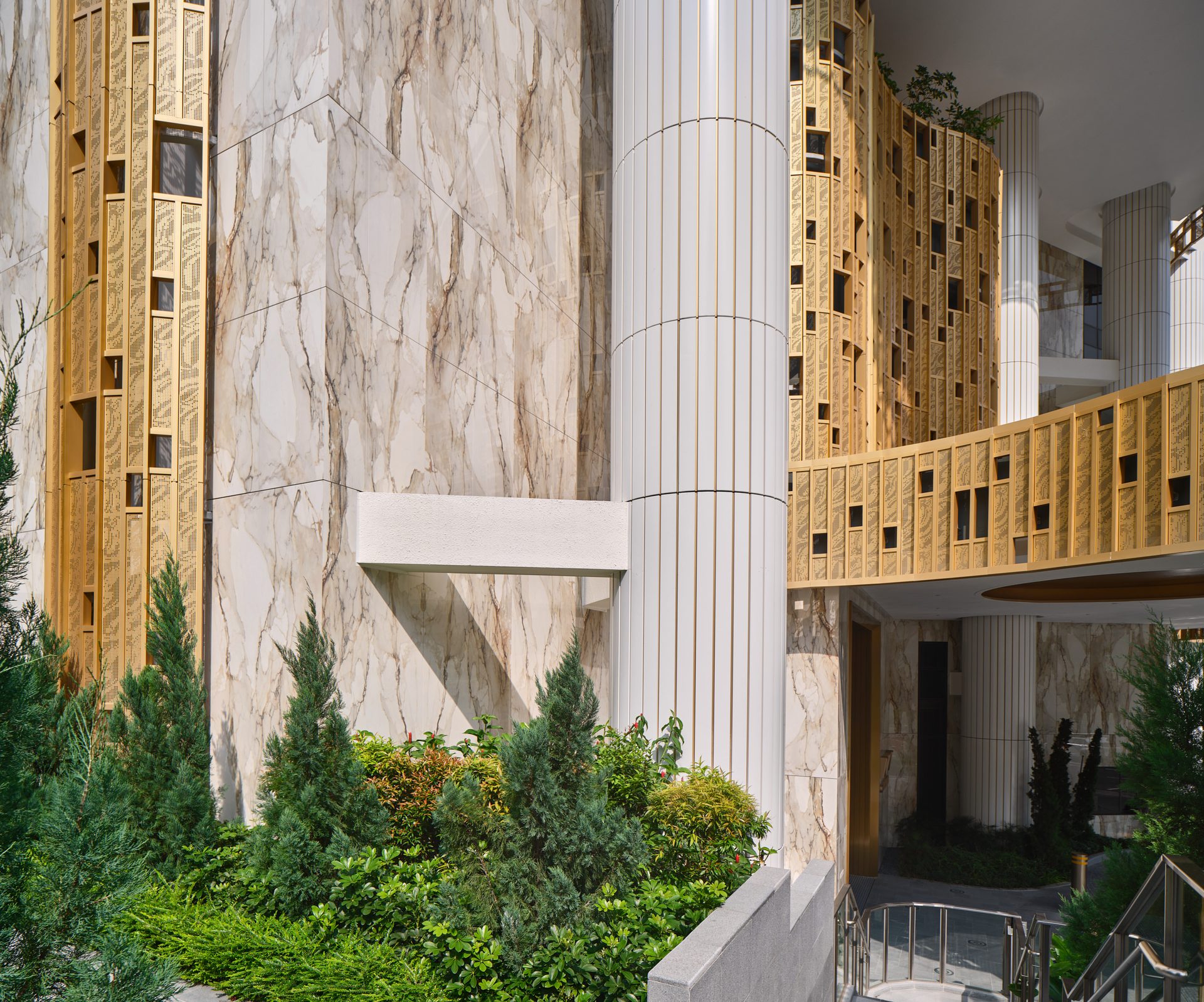 Klimt Cairnhill facade detail showing Atlas Concorde marble-effect porcelain wall, fluted column, and gold mosaic tile cladding