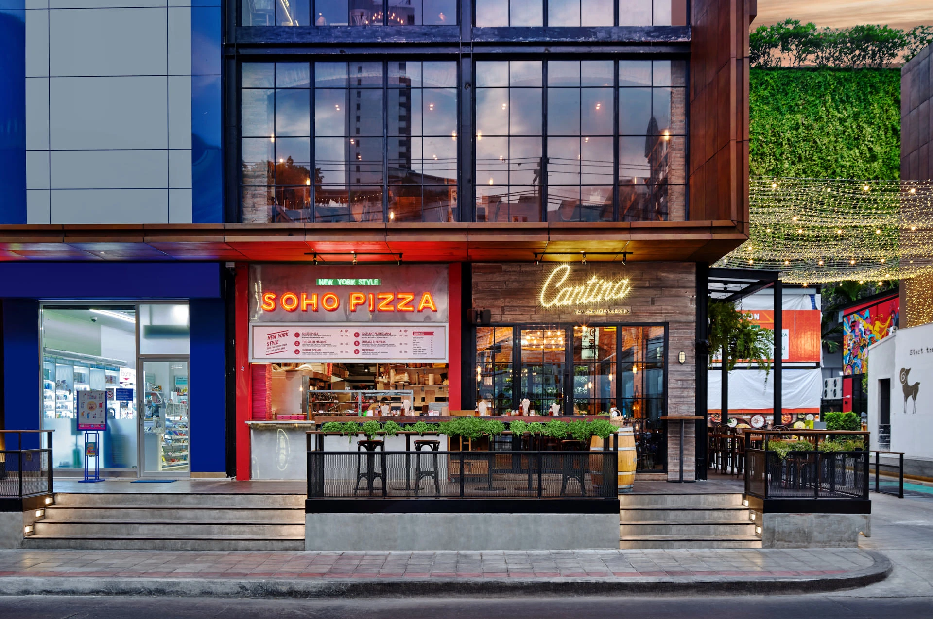 Full facade at dusk with Soho Pizza counter, living wall and string lights — Cantina Bangkok restaurant photography