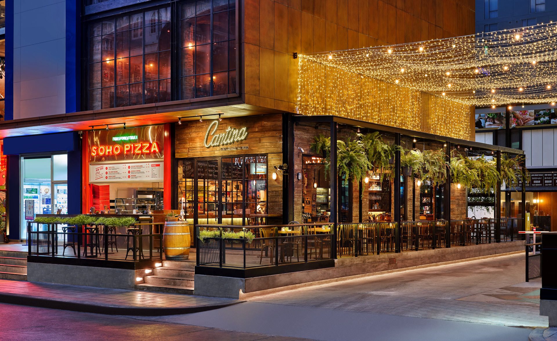 Corner exterior at twilight with neon sign, string lights and wine barrel — Cantina Bangkok restaurant photography
