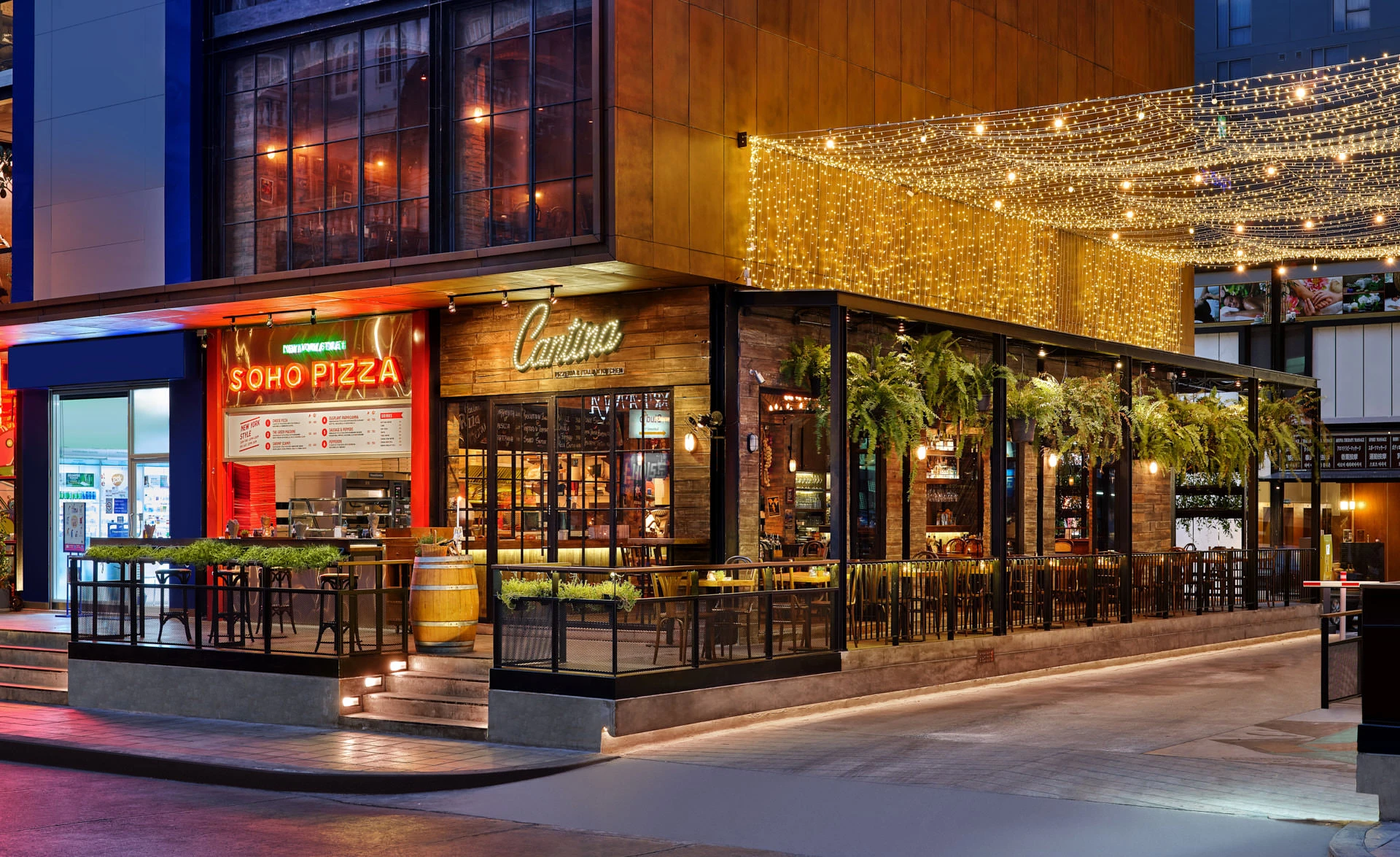 Corner exterior at twilight with neon sign, string lights and wine barrel — Cantina Bangkok restaurant photography