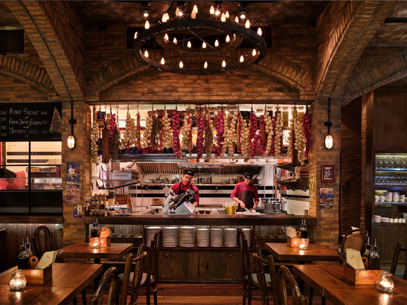 Open kitchen with brick arch, iron chandelier and hanging garlic — Cantina Bangkok restaurant photography