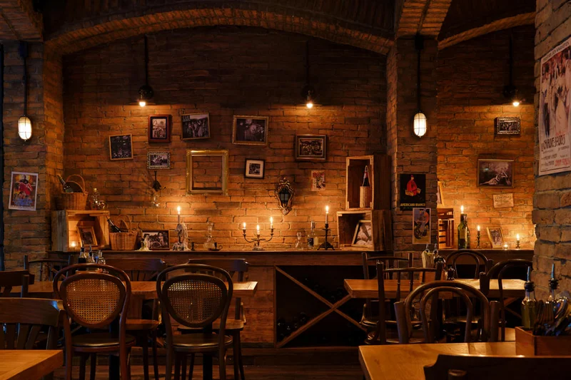 Candlelit brick-walled dining area with wooden tables and warm lighting