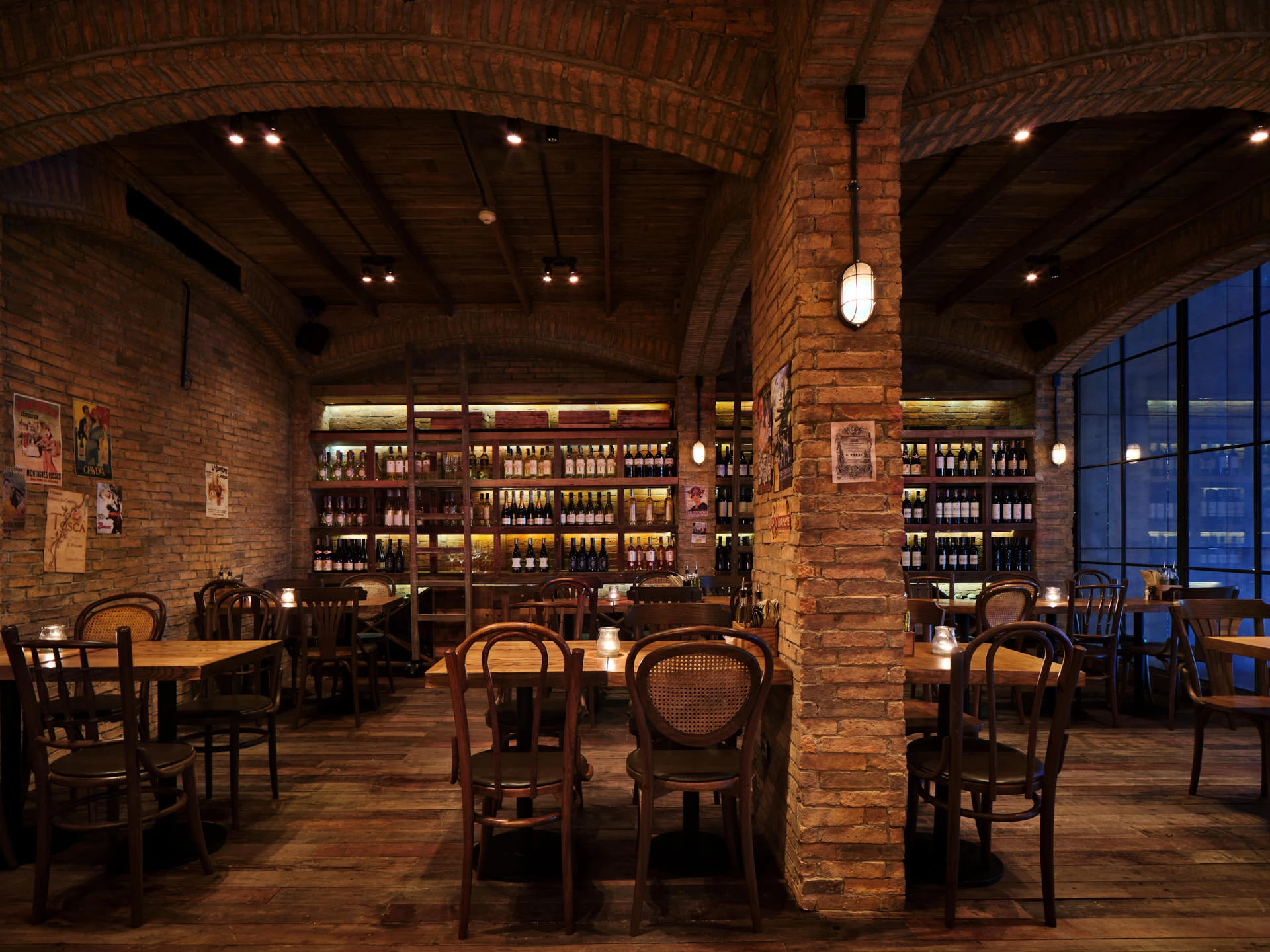 Vaulted brick dining hall with backlit wine wall and opera posters — Cantina Bangkok restaurant interior photography