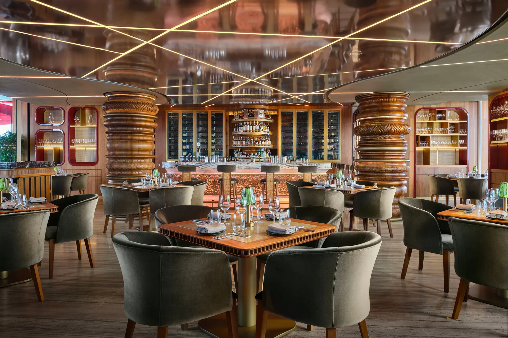 Ce La Vi rooftop restaurant interior with emerald velvet seating, bronze sculptural columns, and geometric mirrored ceiling with golden lighting
