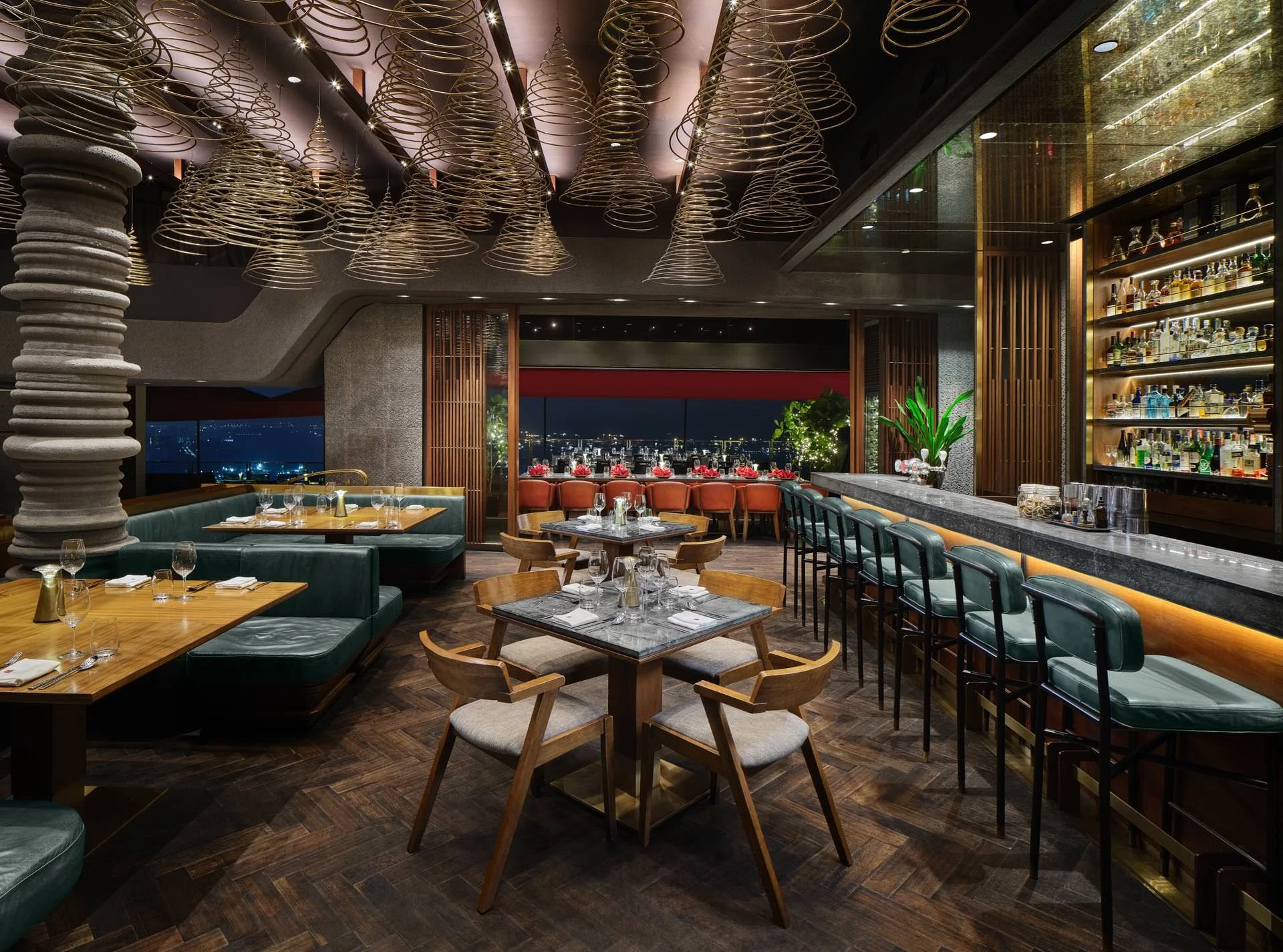 Upper dining level with spiral cone ceiling pendants, herringbone timber floor, teal leather banquettes, mid-century wooden chairs, and a backlit bar with illuminated bottle display at CÉ LA VI Singapore