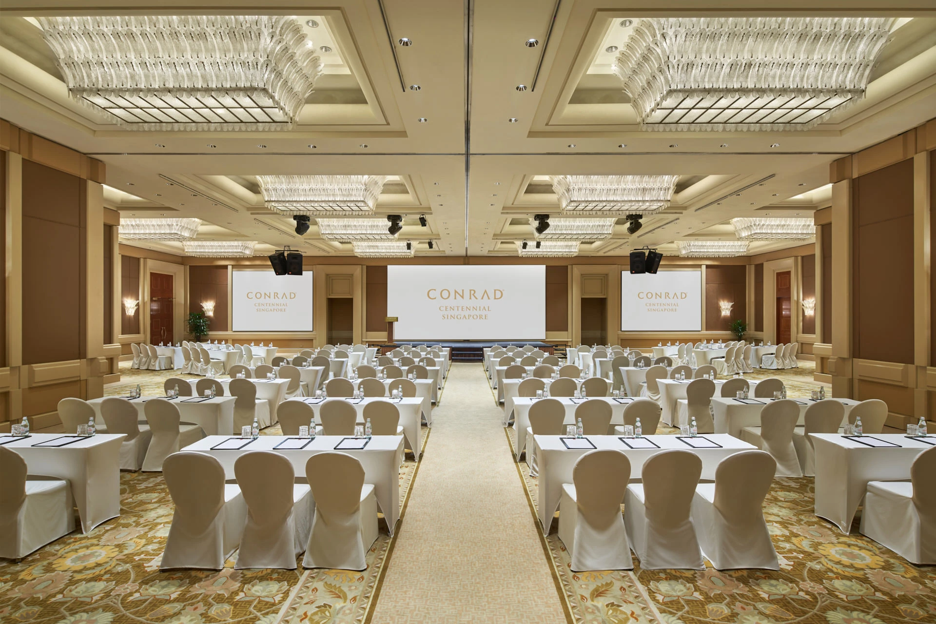 Ballroom classroom with crystal chandeliers, triple screens and stage