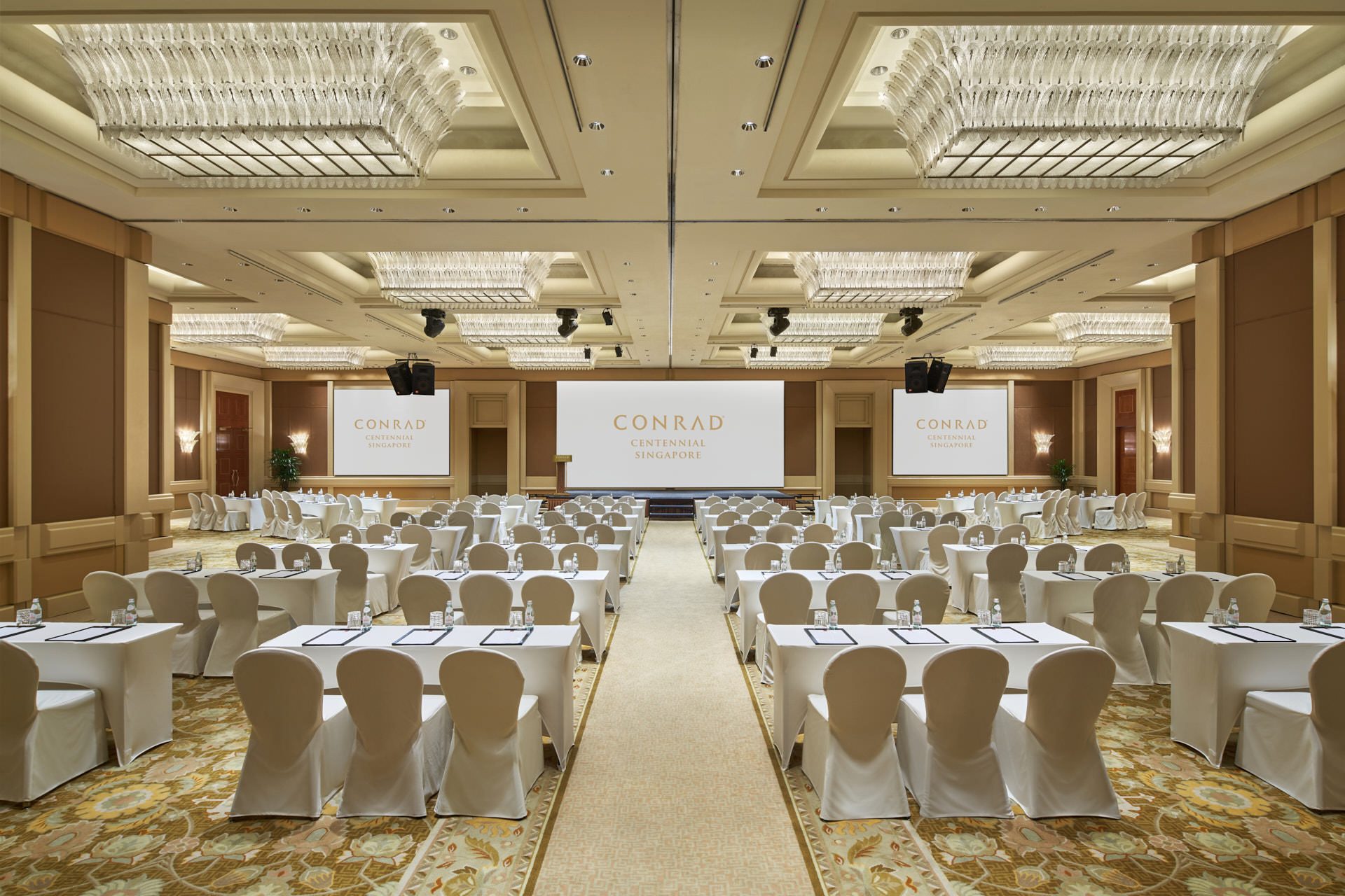 Ballroom classroom with crystal chandeliers, triple screens and stage