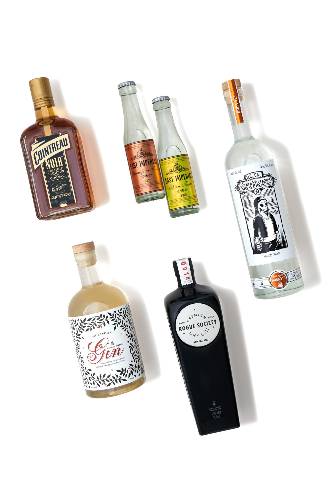 Five spirit bottles on white seamless background with soft studio lighting