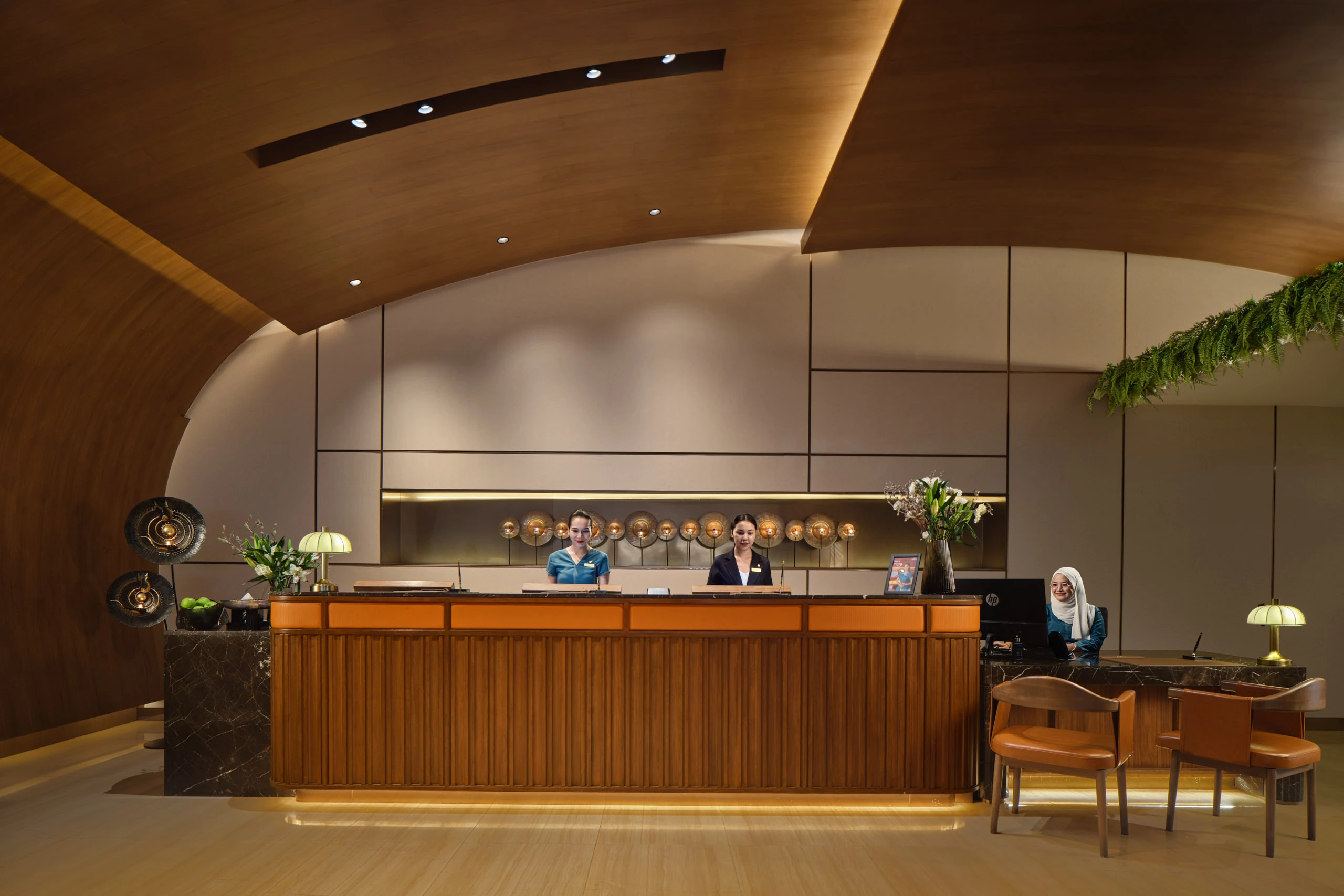 Fraser Suites Sukhumvit front desk with curved timber ceiling and reception staff