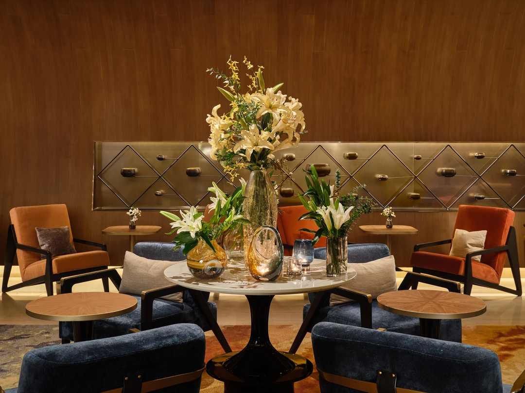 Fraser Suites Sukhumvit lobby floral arrangement with blue velvet chairs and brass wall panel