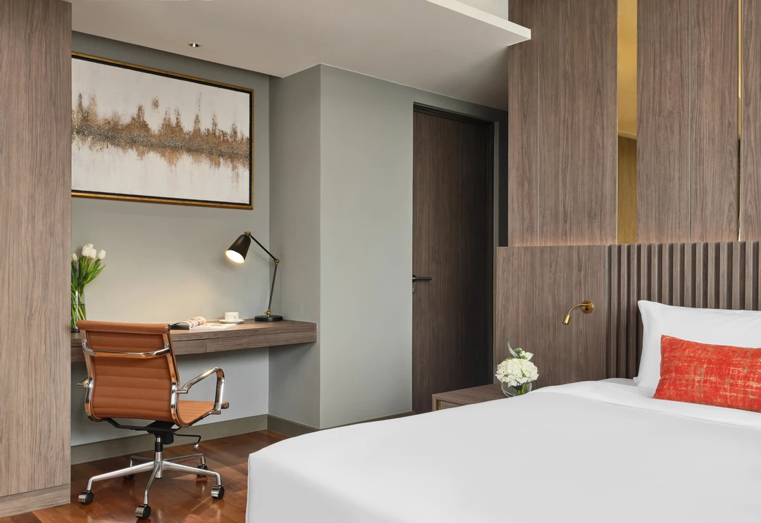 Bedroom desk niche in sage wall with cognac leather chair and artwork