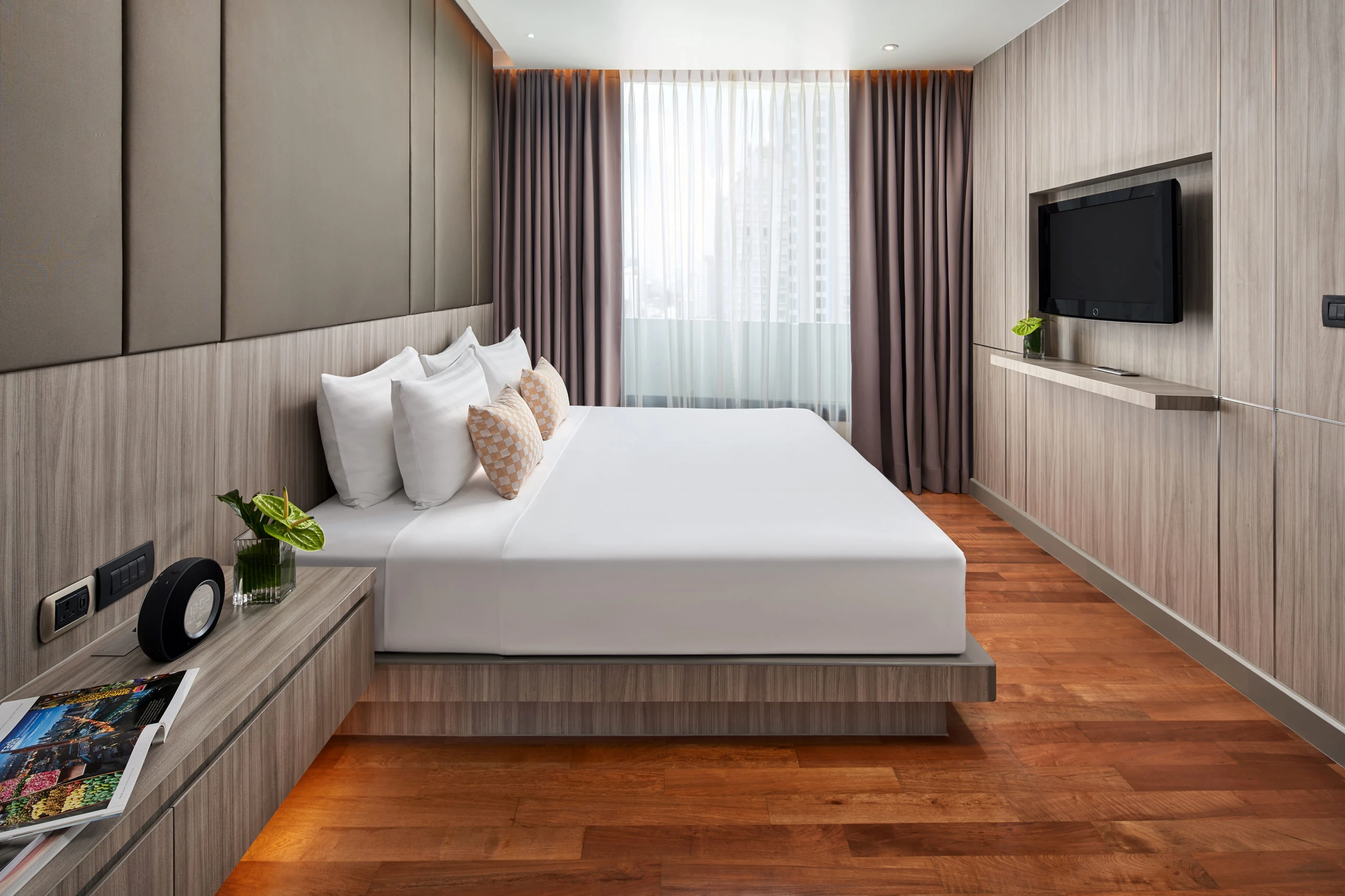 Executive suite bedroom with checkered pillows and wood-grain headboard