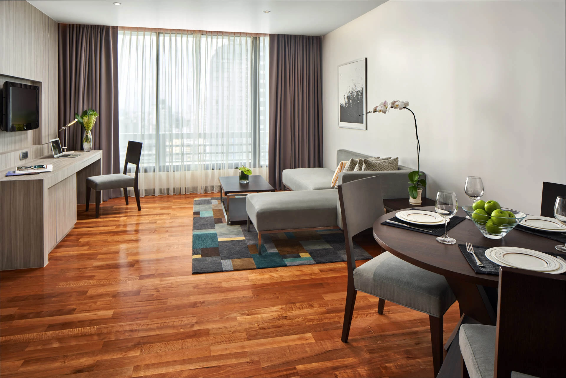 Living-dining area with grey sectional, teal rug and dining table