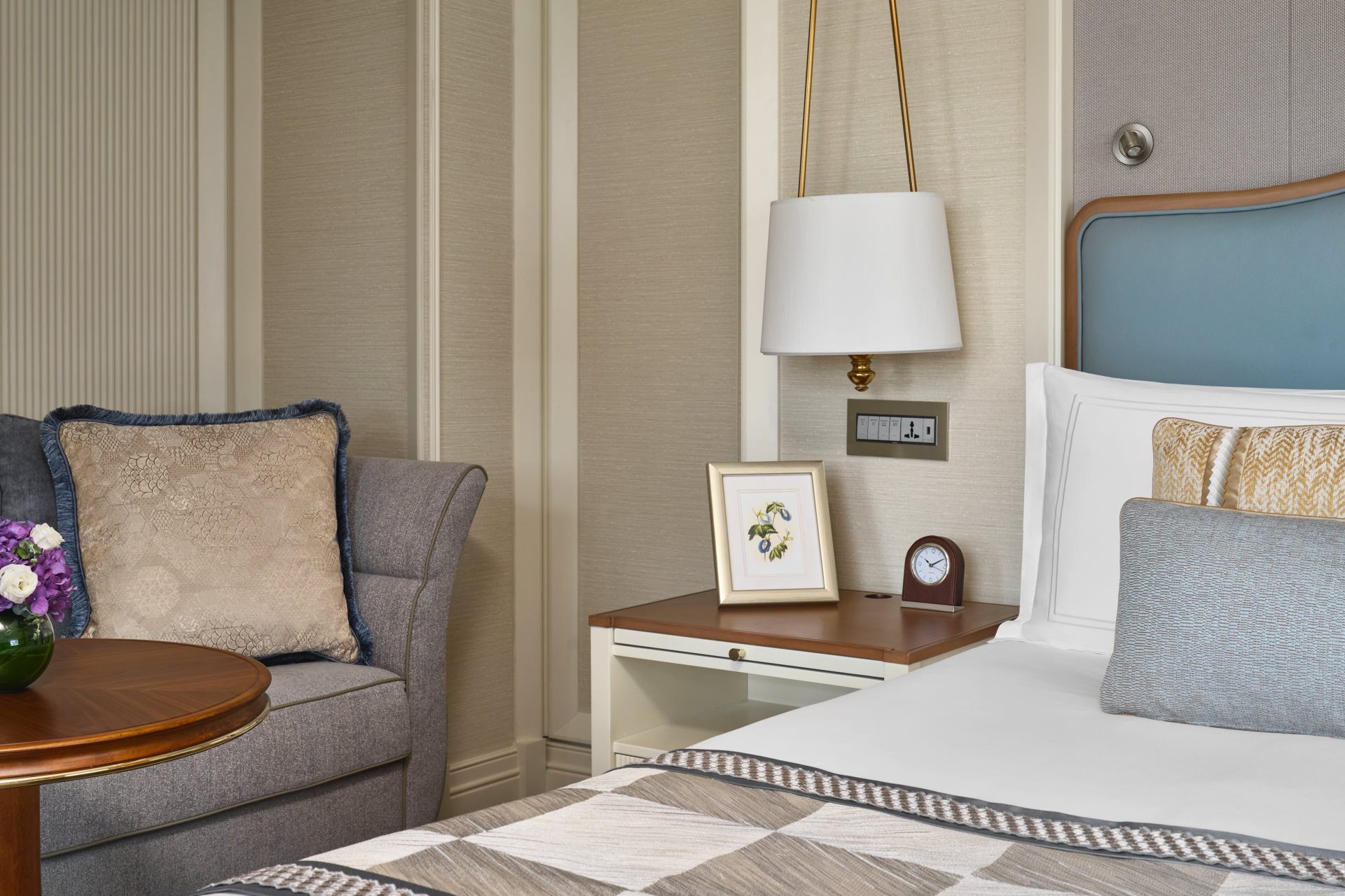 Bedside with wingback chair, botanical print and brass pendant lamp