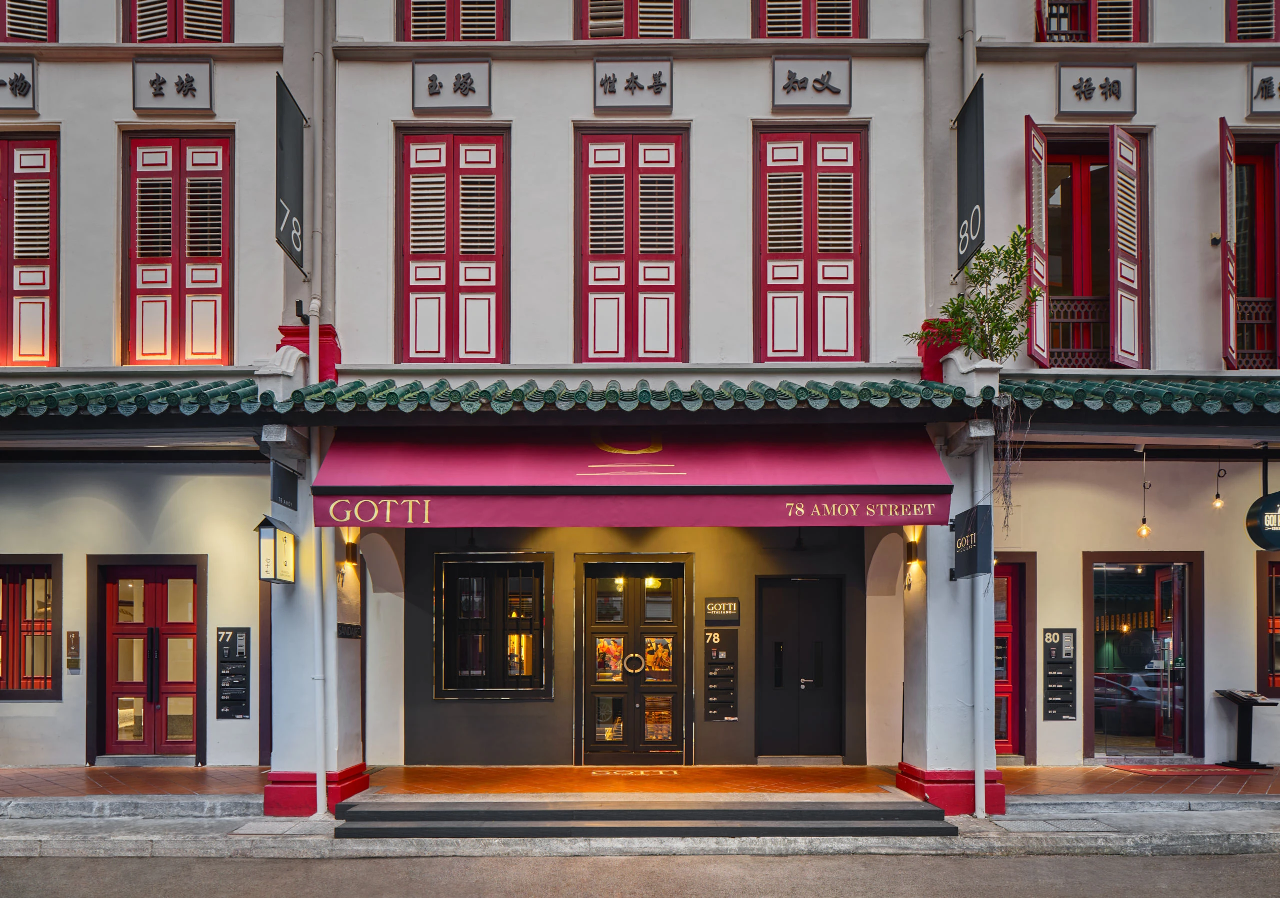 Gotti Singapore historic facade with red windows and warmly lit entrance at dusk