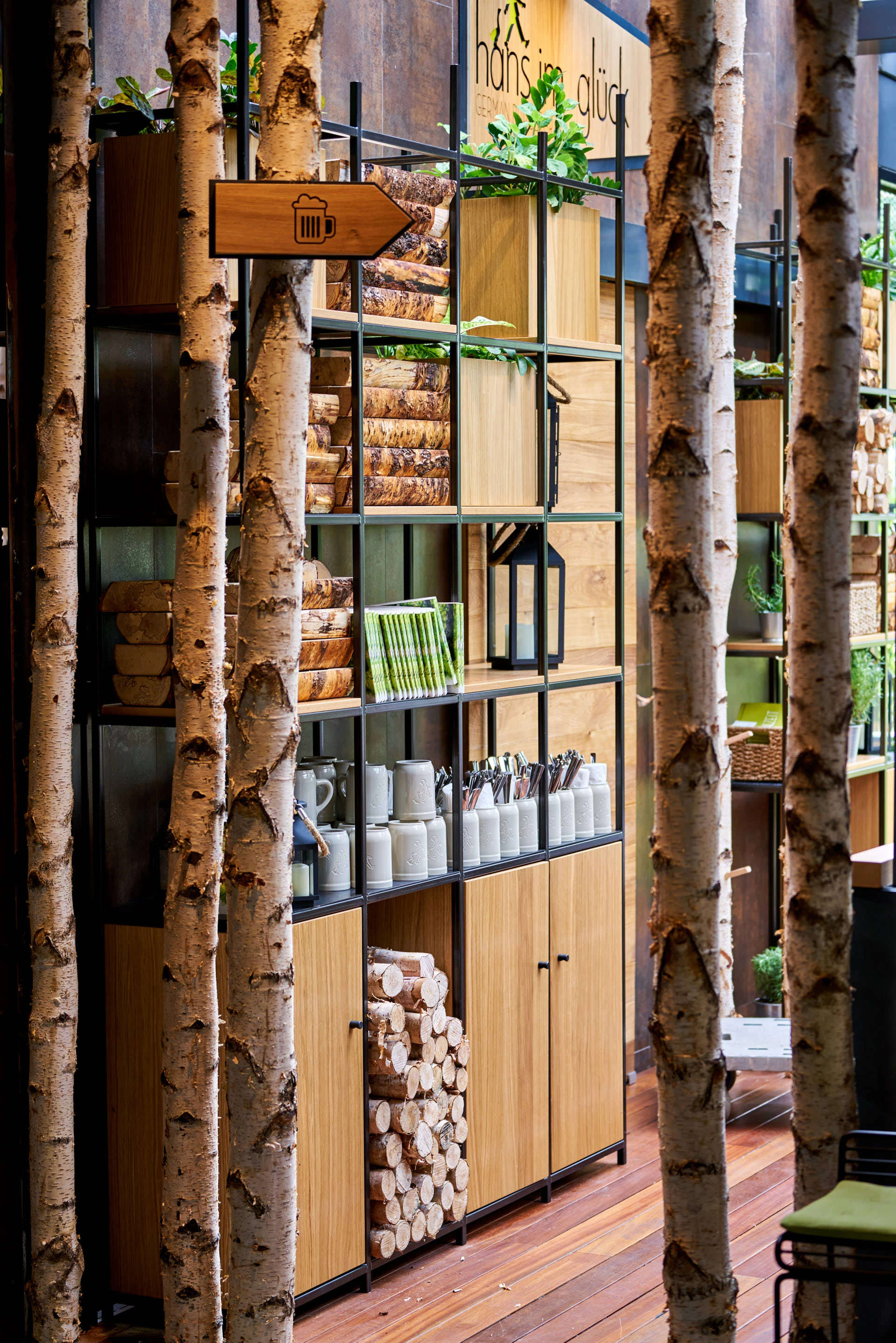 Commercial interior photography detail of WOLF-designed shelving at Hans Im Gluck, featuring stacked logs and minimalist decor elements.