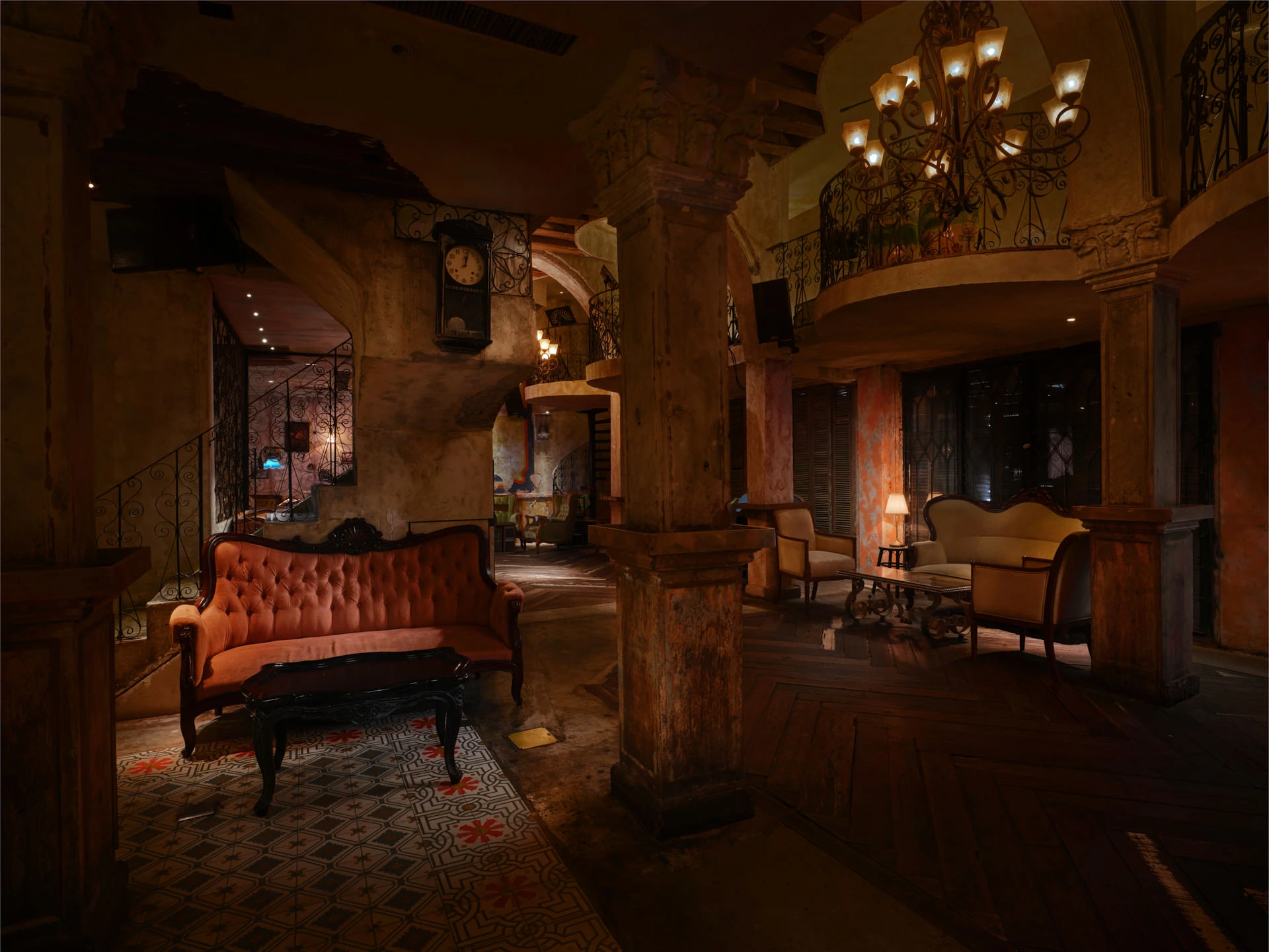 Double-height salon with iron chandelier, mezzanine balcony and tufted sofas — Havana Social Bangkok restaurant photography