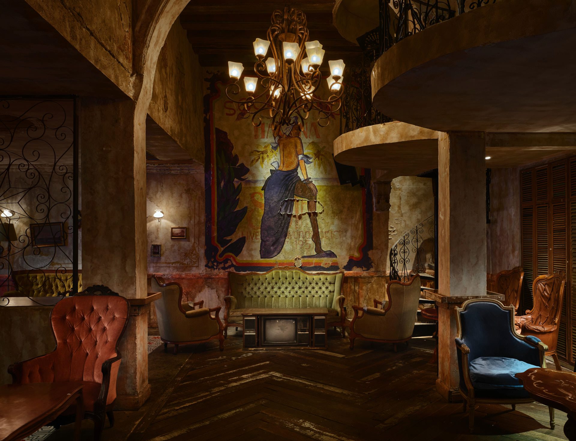 Cuban mural with distressed walls, tufted settee and iron chandelier — Havana Social Bangkok interior photography