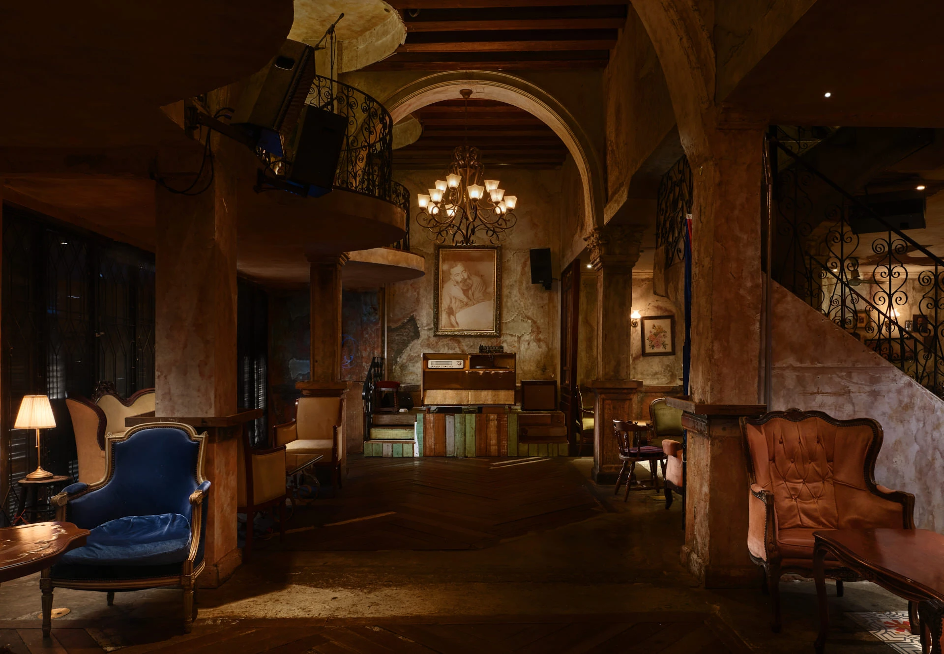 Speakeasy lounge with vintage armchairs, iron chandelier and performance stage — Havana Social Bangkok interior photography