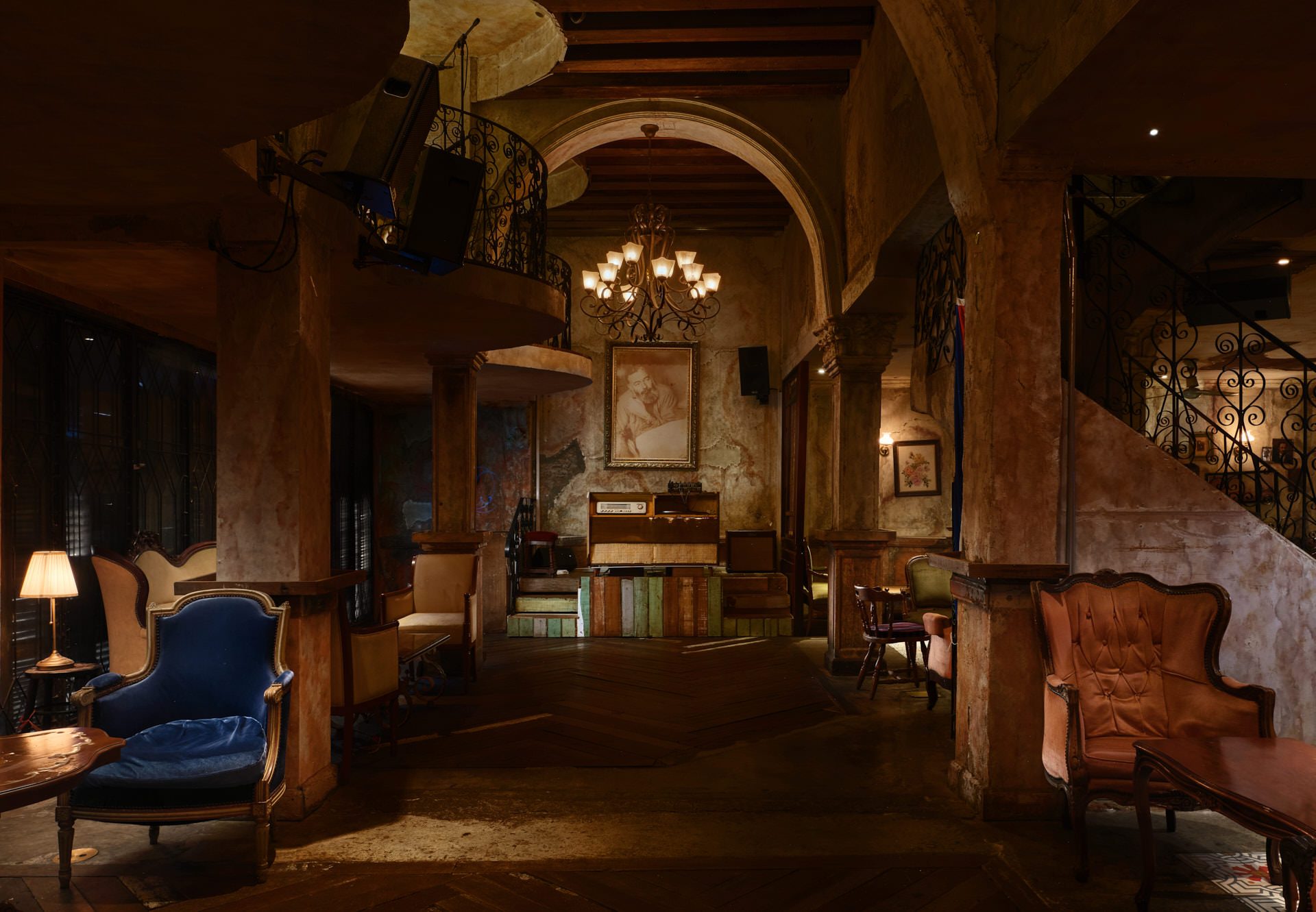 Speakeasy lounge with vintage armchairs, iron chandelier and performance stage — Havana Social Bangkok interior photography