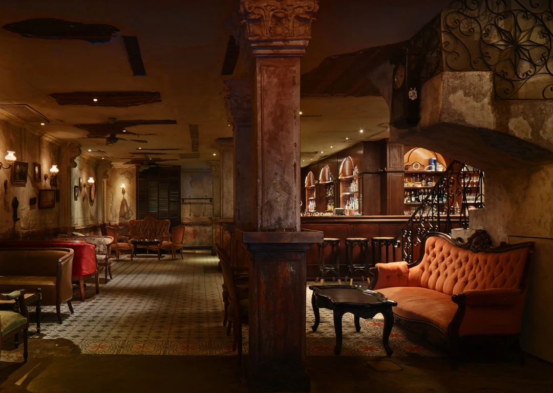 Full venue with mahogany bar, weathered columns and vintage sconces — Havana Social Bangkok interior photography
