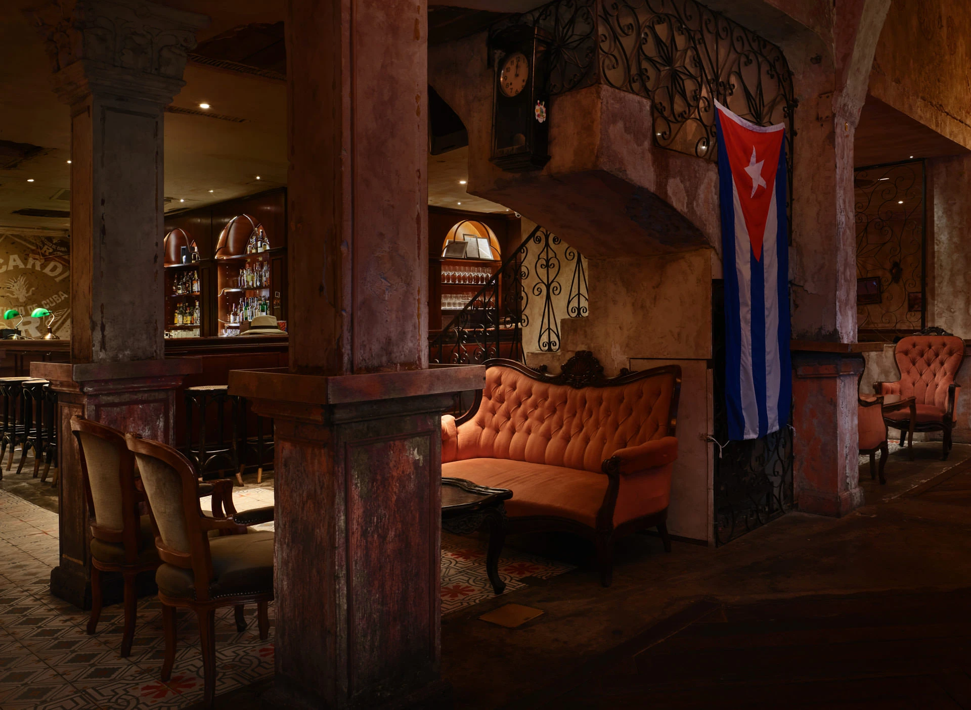 Bar with Bacardi sign, coral sofa and spiral staircase with Cuban flag — Havana Social Bangkok restaurant photography