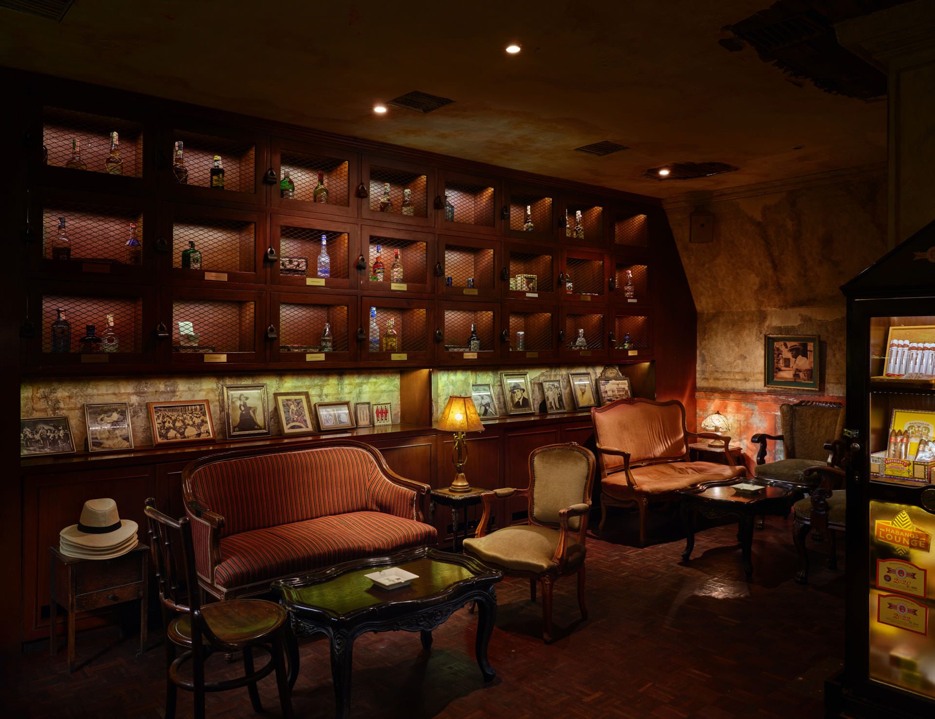 Private cigar lounge with liquor cabinets, leather chairs and Panama hats — Havana Social Bangkok restaurant photography