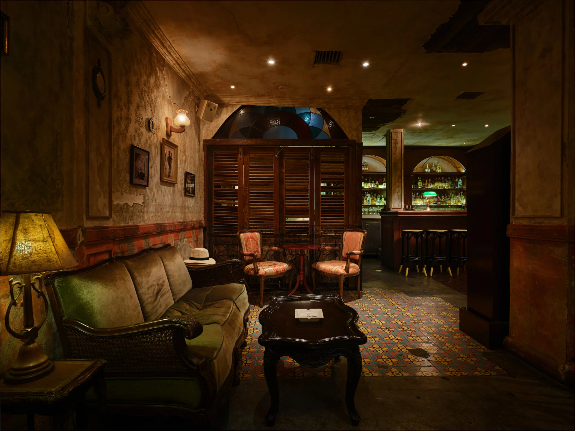 Lounge with green velvet sofa, louvered doors and stained-glass transom — Havana Social Bangkok interior photography