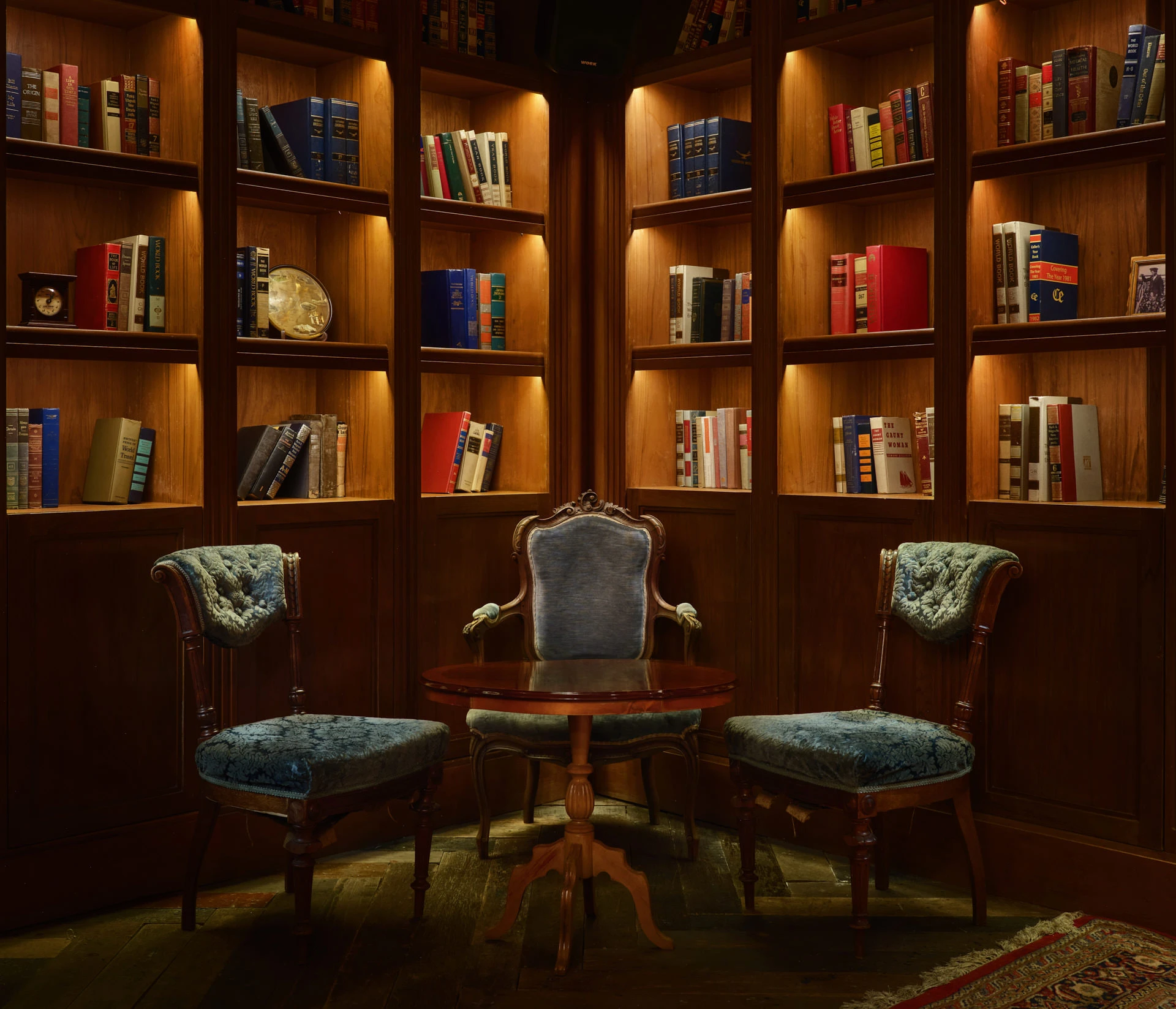 Library nook with blue velvet chairs, bookshelves and amber shelf lighting — Havana Social Bangkok interior photography