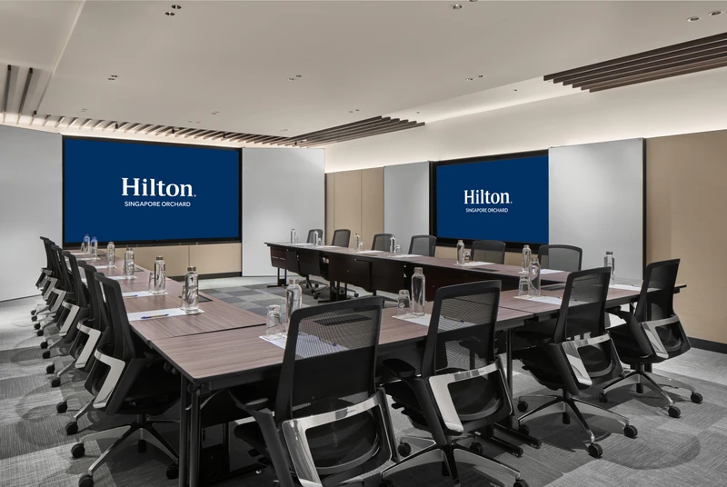 Hilton Singapore Orchard Level 5 Rhu in U-shape setup with modern hotel meeting room seating and integrated presentation screens