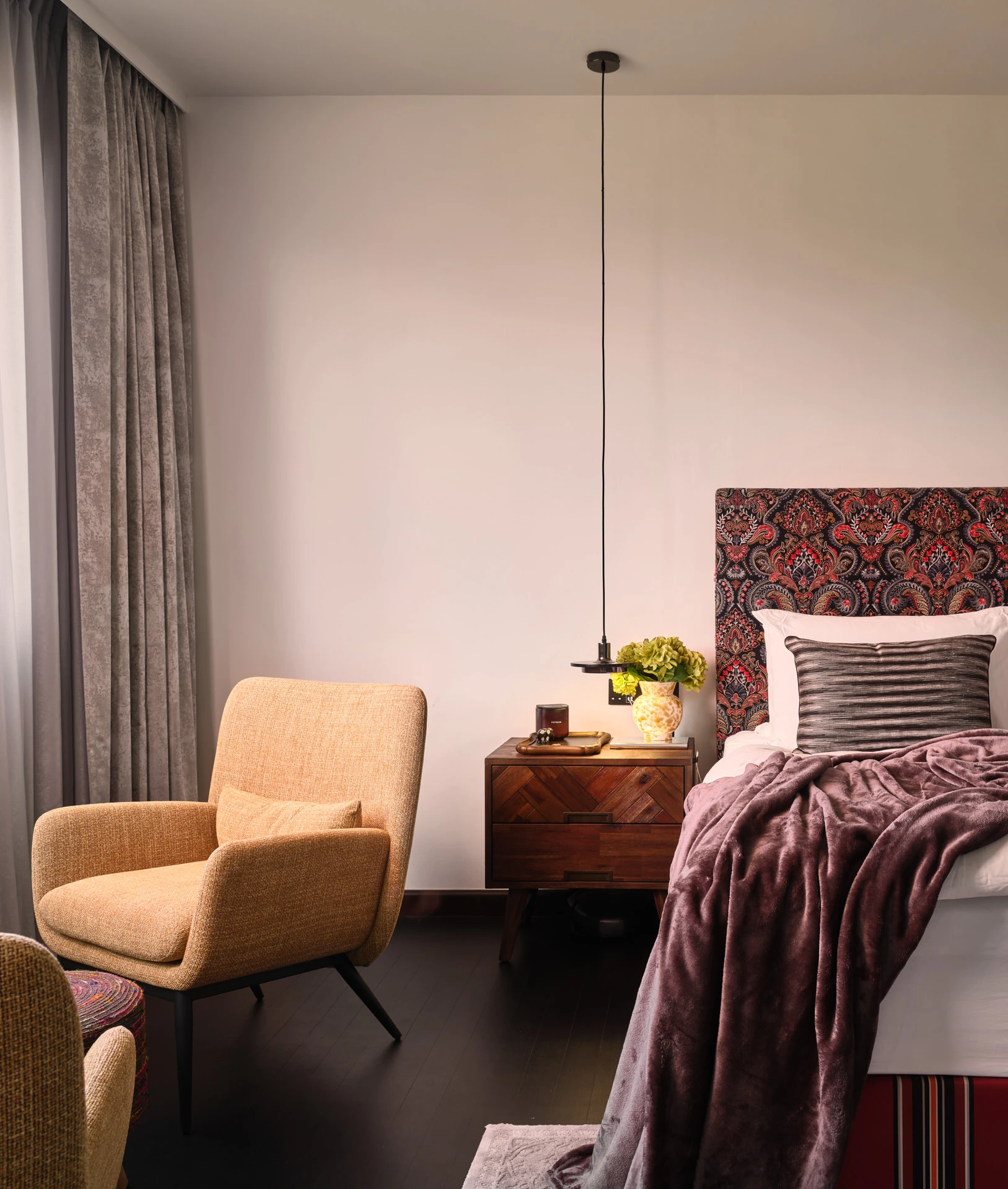 Bedroom with paisley headboard, aubergine throw and mustard armchair